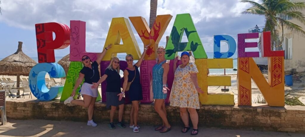 Mackenzie and fellow travel agents posing in front of the colorful Playa del Carmen sign, enjoying a fun-filled day visiting Palace Resorts locations in Mexico's Riviera Maya