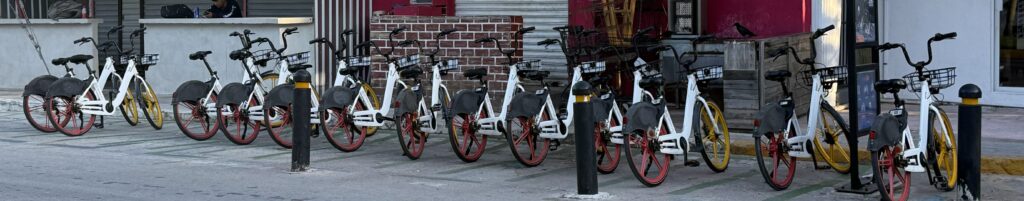 Bicycles lined up in front of stores in Playa del Carmen, showcasing the ease of using the Biciplaya app for exploring the city