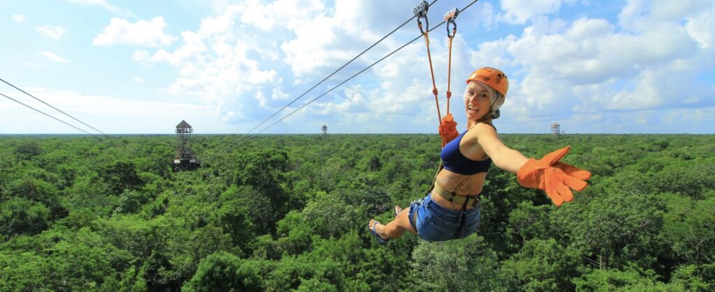 Women zip-lining on an excursion in Playa del Carmen, surrounded by lush greenery and natural scenery