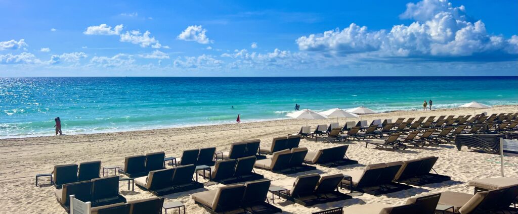 Looking out over the beach at Beach Palace Resort onto the Caribbean Sea, featuring sun chairs set up and ready for guests to enjoy the stunning view