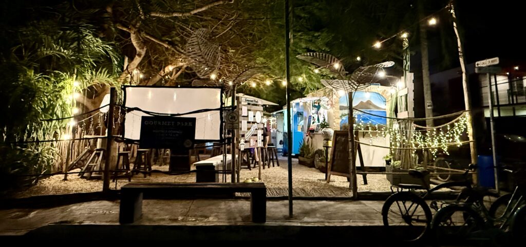 A street view of Gourmet Park in Playa del Carmen, featuring its welcoming entrance, lush greenery, and bustling energy