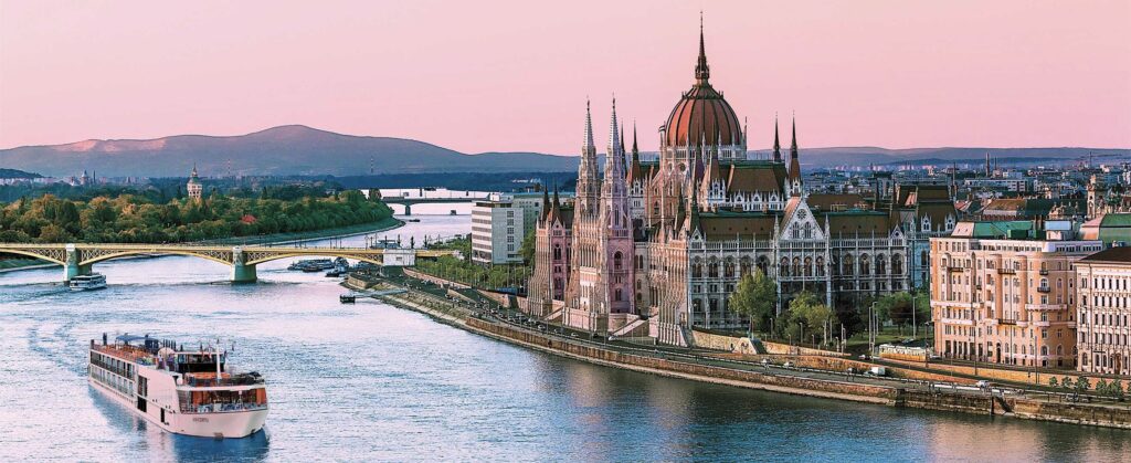 AmaWaterways cruising down a picturesque river with a charming European city in the background, featuring historic architecture and lush greenery along the riverside, creating a serene and captivating scene