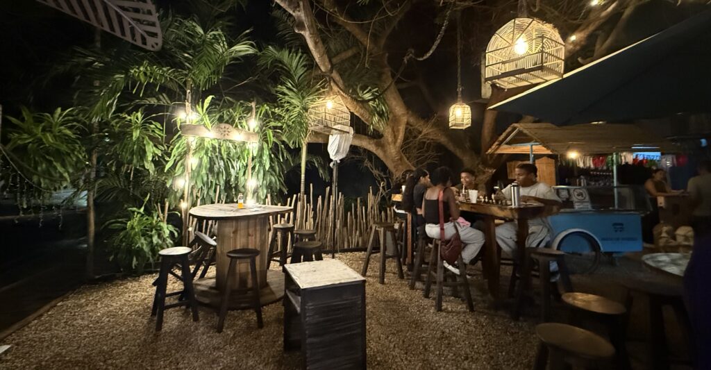 An inviting outdoor seating area at Gourmet Park with empty tables, string lights, and a laid-back tropical ambiance, perfect for relaxing meals