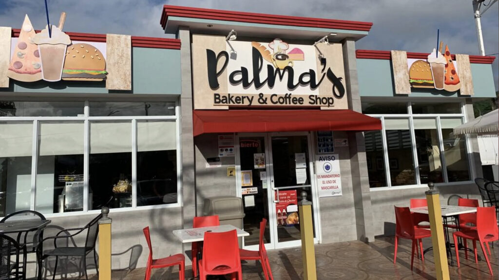 Exterior view of Palmas Bakery in Puerto Rico with a sitting area and front door, creating a welcoming and cozy atmosphere