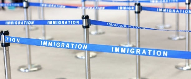 Travelers waiting in an immigration line at the airport with luggage and passports in hand, highlighting visa-free travel.