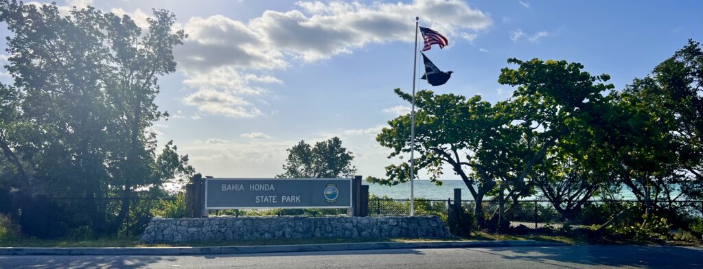 Welcome sign at Bahia Honda State Park in Florida Keys, featuring lush greenery and a scenic coastal view, inviting visitors to explore this beautiful natural park