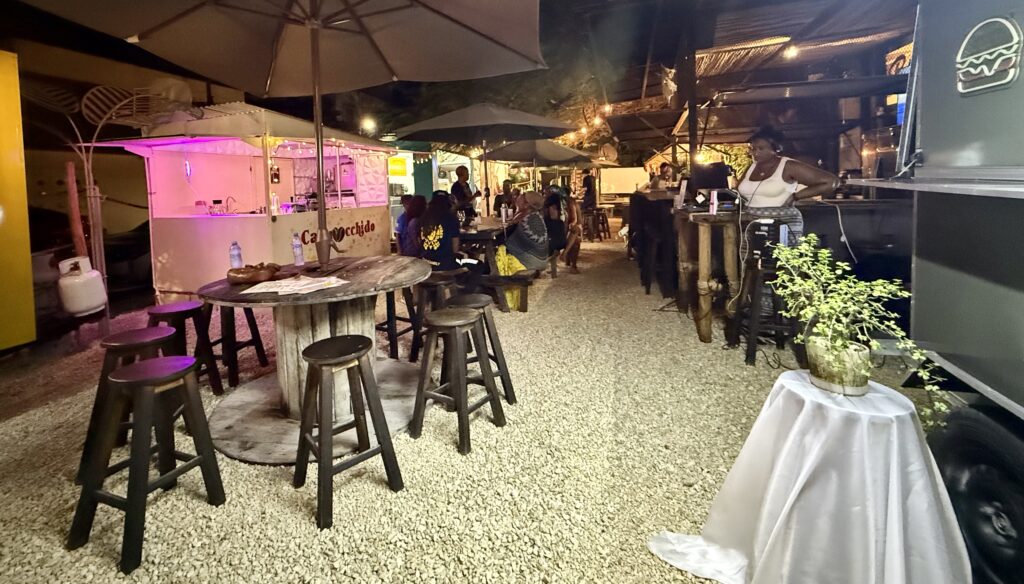 A wide-angle view of Gourmet Park in Playa del Carmen, showcasing its vibrant food trucks, seating areas, and lively atmosphere under the clear sky