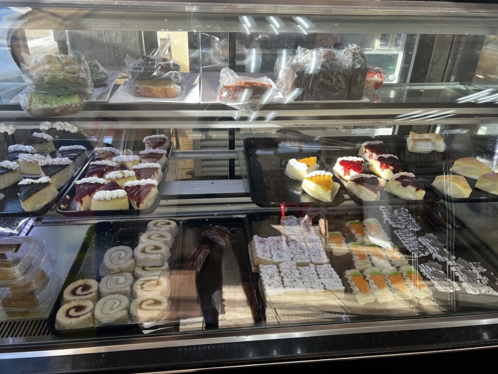 Sweets case at Palmas Bakery in Puerto Rico, featuring cheesecakes and a variety of traditional pastries and desserts