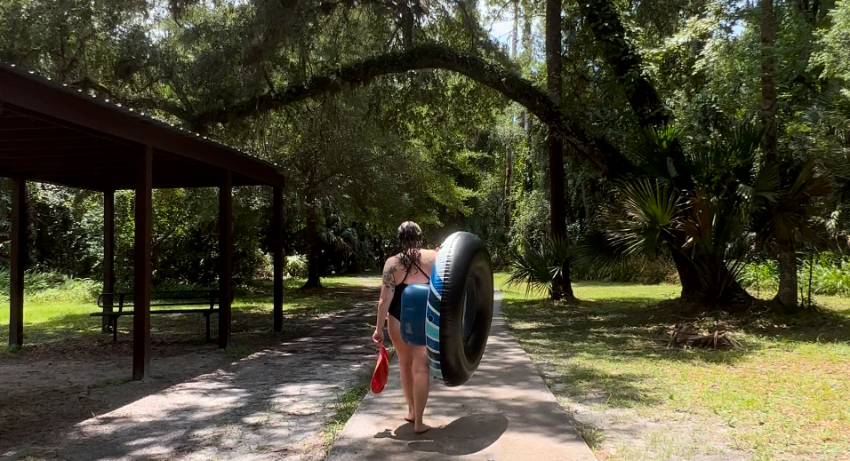 Person carrying their tube back to the start of Kelly Park Rock Springs, ready to enjoy another lap through the clear blue waters and lush surroundings