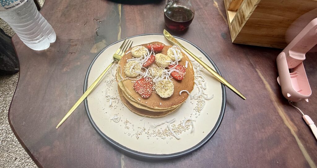 Fluffy pancakes topped with fresh fruit at The Green Kitchen in Playa del Carmen, a healthy and flavorful breakfast choice made with organic ingredients. One of this restaurants best dishes