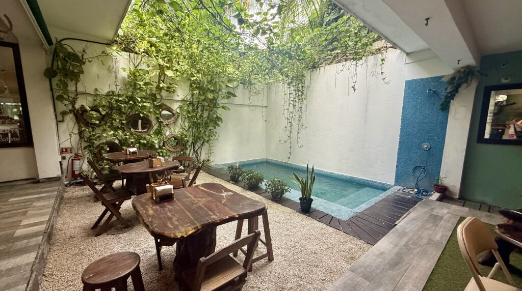 Beautiful outdoor pool and dining tables at The Green Kitchen in Playa del Carmen, providing a tranquil setting for enjoying delicious meals and drinks in a serene environment